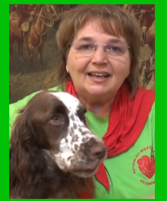Agota is smiling at the camera with her arm around a Springer Spaniel 