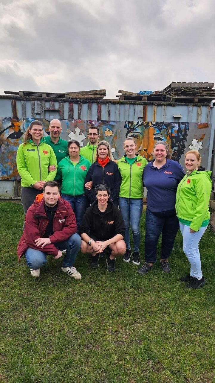 A group of people posing for the camera outside. Some are wearing With Dogs for a Smile shirts and some Os'mose shirts