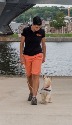 Vanessa is walking with a puppy on leash. She is looking down at the puppy and the puppy is looking up at her.