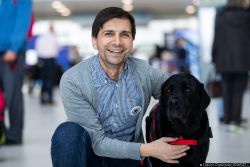 Marijan is kneeling down with a black labrador next to him.
