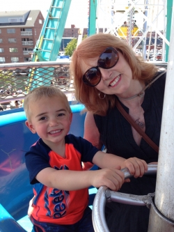 Sheila is smiling at the camera. Her young grandson is sitting next to her.