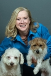 Michele Ostrander is smiling at the camera while holding a small dog in each arm.